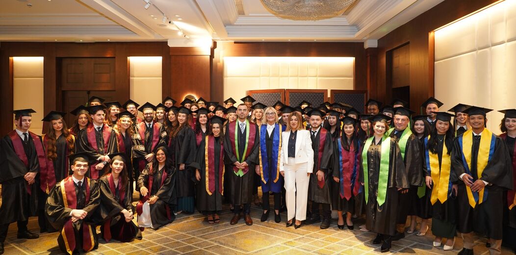 George Ntemos standing among graduating students in caps and gowns.